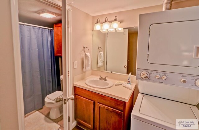 bathroom featuring tile patterned flooring, stacked washer and dryer, toilet, vanity, and a shower with shower curtain