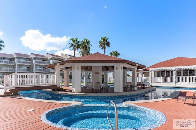 view of pool featuring an outdoor bar, a gazebo, a hot tub, and a wooden deck