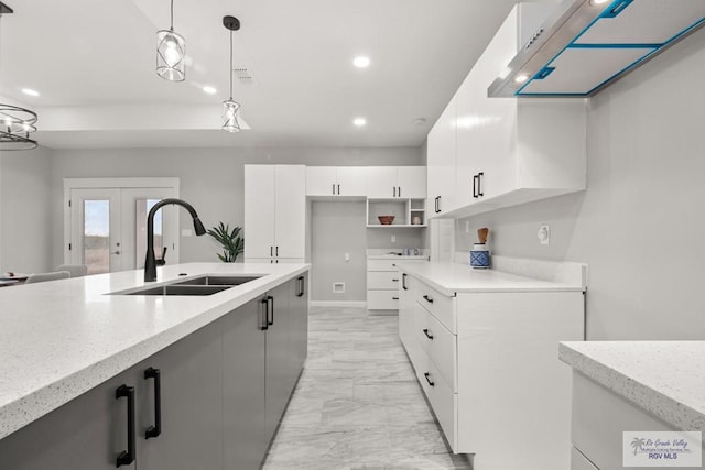 kitchen with sink, white cabinetry, pendant lighting, french doors, and light stone countertops