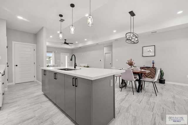 kitchen featuring a center island with sink, gray cabinetry, ceiling fan, pendant lighting, and sink