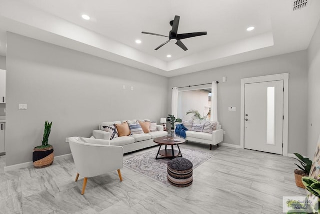 living room featuring a tray ceiling and ceiling fan