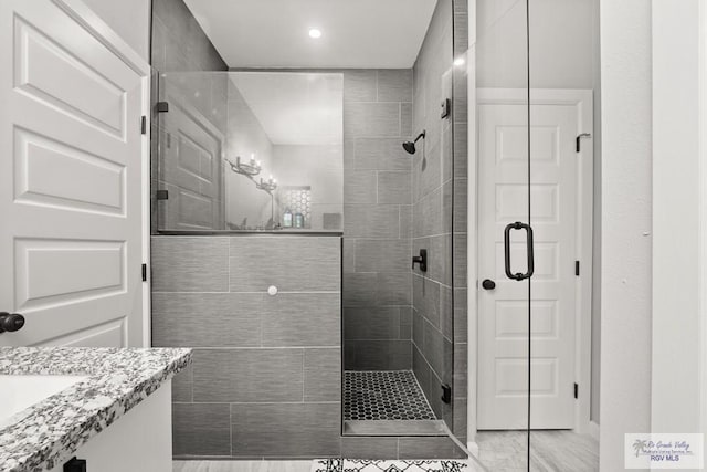 bathroom with a shower with shower door and vanity