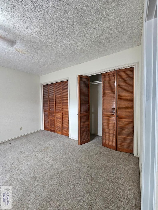 unfurnished bedroom with ceiling fan, a textured ceiling, multiple closets, and carpet