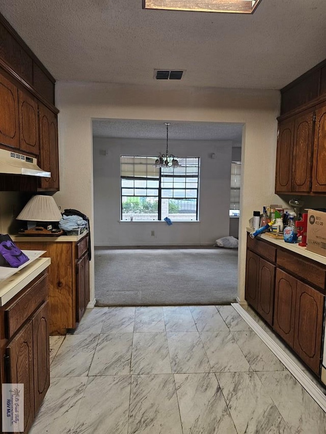 kitchen featuring pendant lighting, dark brown cabinetry, and an inviting chandelier