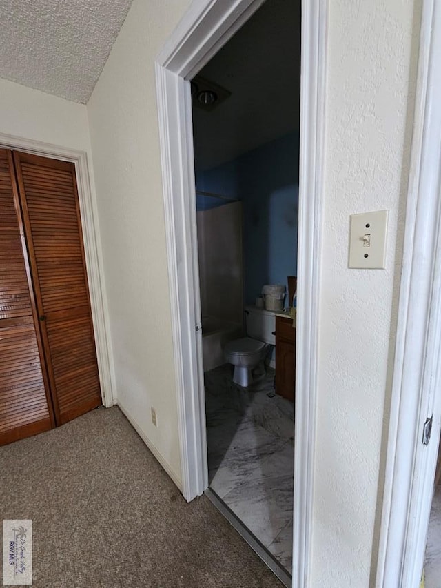 hall featuring a textured ceiling and carpet