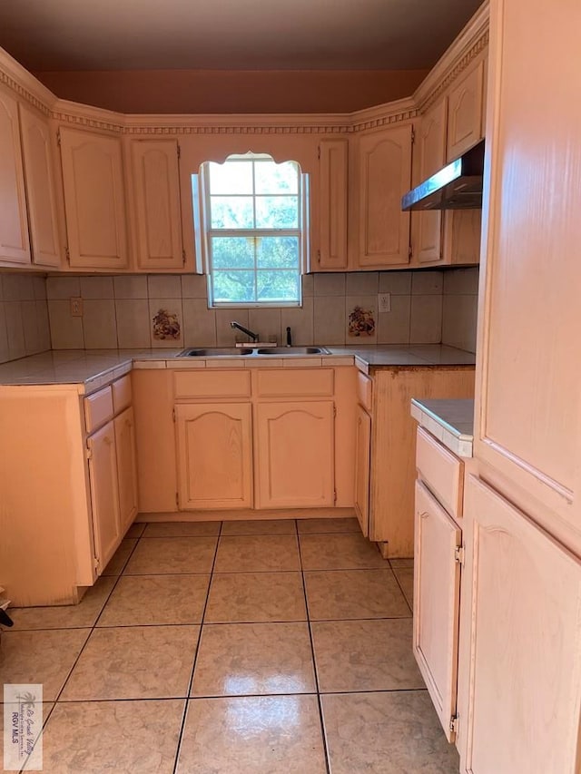 kitchen featuring decorative backsplash, light tile patterned floors, and sink