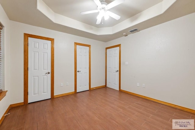 5662 Rustic Manor Dr, Brownsville, TX 78526 - unfurnished bedroom with a tray ceiling, baseboards, wood finished floors, and ceiling fan