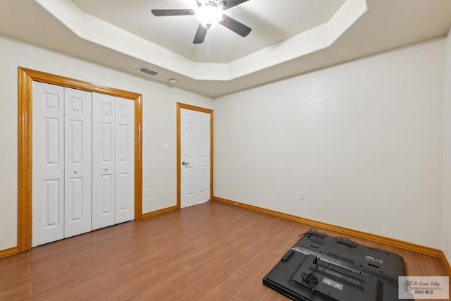 5662 Rustic Manor Dr, Brownsville, TX 78526 - unfurnished bedroom with a tray ceiling, wood finished floors, baseboards, a ceiling fan, and a closet