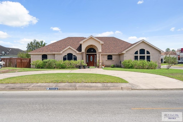 5662 Rustic Manor Dr, Brownsville, TX 78526 - view of front of property with brick siding, curved driveway, and a shingled roof