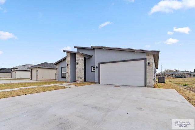 473 Santiago St, La Feria, TX 78559 - view of front of home with central air condition unit, stucco siding, driveway, stone siding, and an attached garage