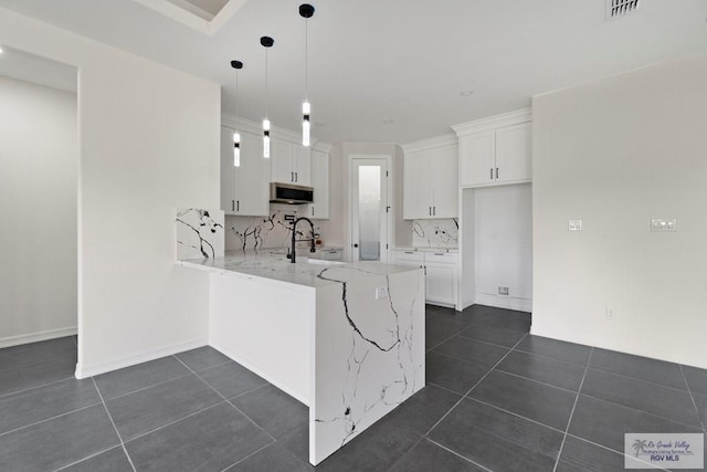 473 Santiago St, La Feria, TX 78559 - kitchen featuring stainless steel microwave, dark tile patterned floors, a peninsula, and a sink
