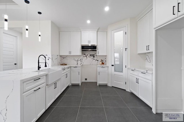 473 Santiago St, La Feria, TX 78559 - kitchen with dark tile patterned flooring, a sink, stainless steel microwave, backsplash, and a peninsula