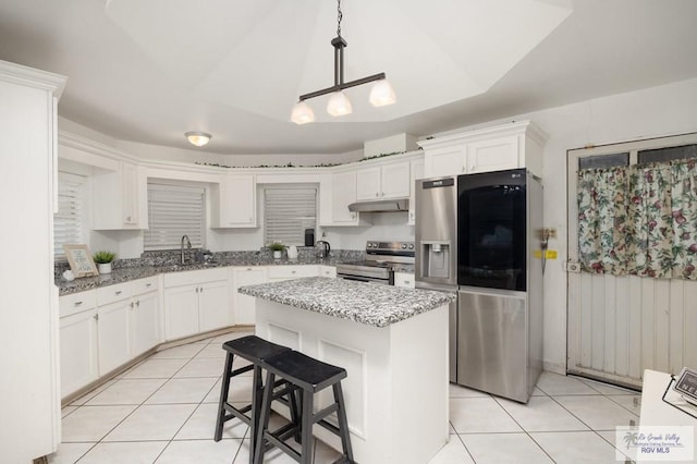 kitchen with stainless steel appliances, sink, pendant lighting, a kitchen island, and light tile patterned flooring