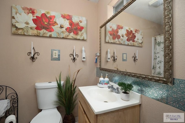 bathroom with vanity, toilet, and tasteful backsplash