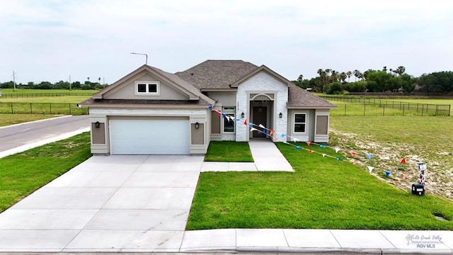 23547 Murphy Ct, Harlingen, TX 78552 - view of front facade featuring a garage, driveway, a view of countryside, a shingled roof, and stucco siding