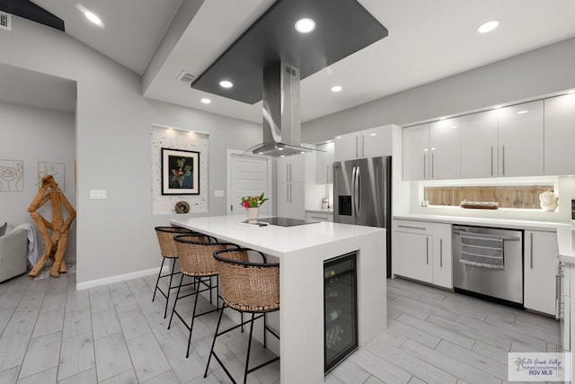 269 Cameo Dr, San Benito, TX 78586 - kitchen featuring appliances with stainless steel finishes, wine cooler, island exhaust hood, modern cabinets, and a kitchen breakfast bar