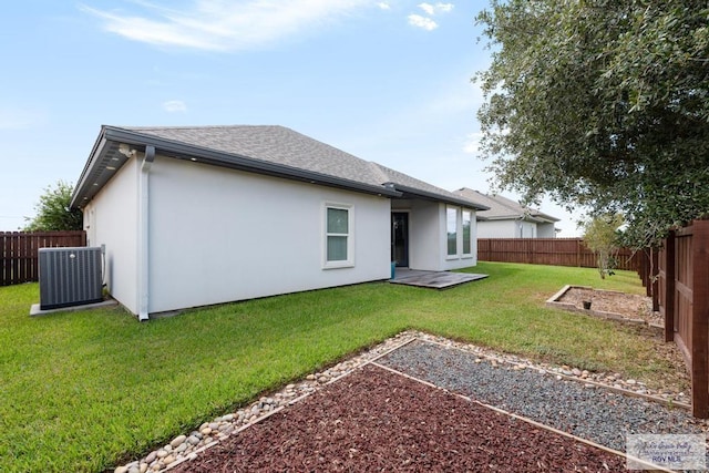 rear view of house with central AC and a lawn