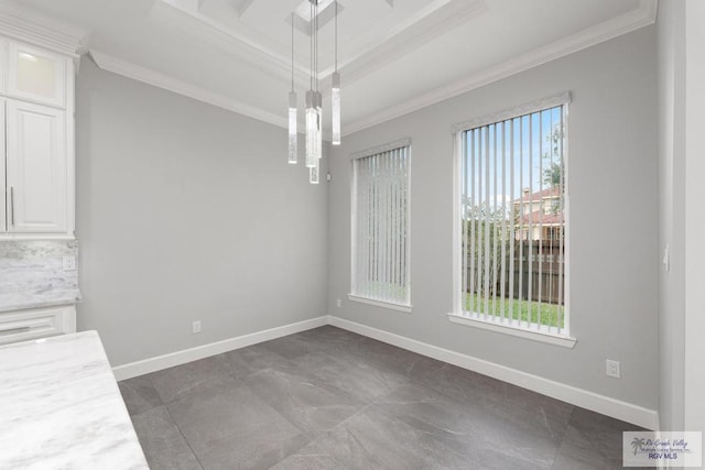 unfurnished dining area with a raised ceiling and crown molding