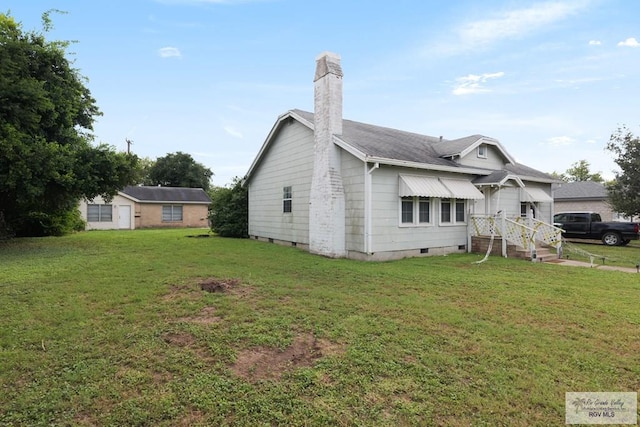 view of side of home with crawl space, a lawn, and a chimney