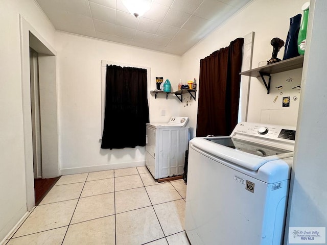 laundry area with light tile patterned floors, laundry area, independent washer and dryer, and baseboards