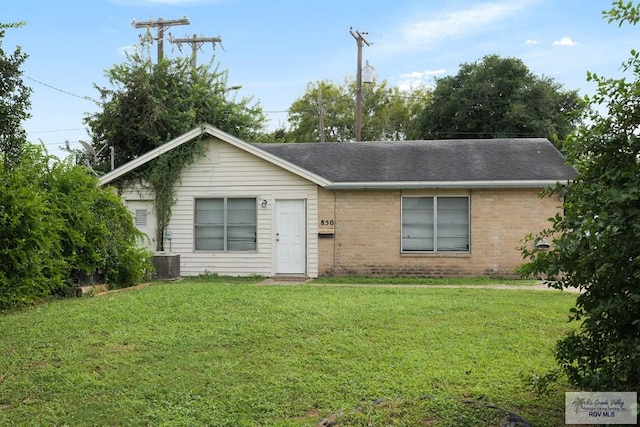 single story home featuring cooling unit, brick siding, a front lawn, and roof with shingles