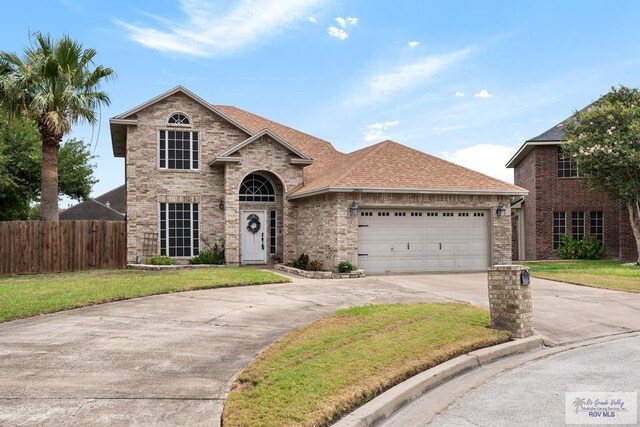 2853 Fleet St, Brownsville, TX 78521 - traditional home with driveway, a garage, brick siding, and roof with shingles