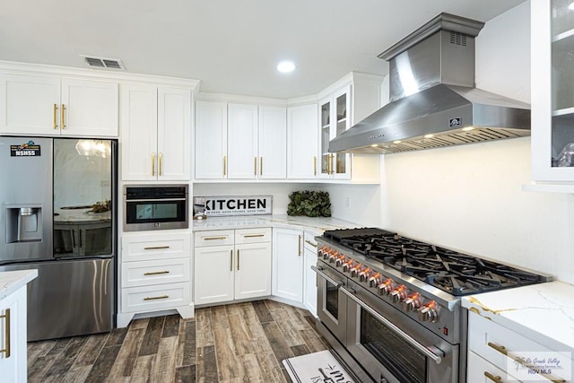 kitchen with appliances with stainless steel finishes, dark hardwood / wood-style floors, ventilation hood, white cabinetry, and light stone countertops