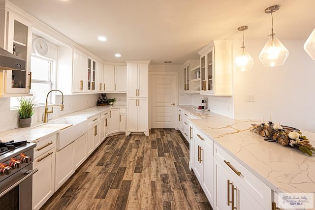 kitchen with pendant lighting, white cabinetry, sink, high end range, and light stone counters