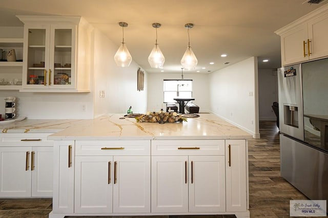 kitchen with hanging light fixtures, light stone countertops, white cabinets, and stainless steel refrigerator with ice dispenser