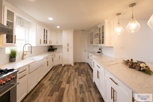 kitchen featuring sink, white cabinetry, hanging light fixtures, stainless steel stove, and light stone countertops