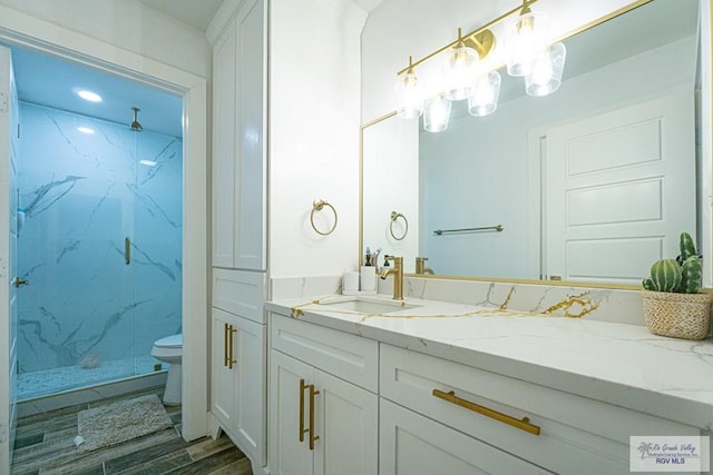 bathroom with vanity, toilet, hardwood / wood-style floors, and a tile shower