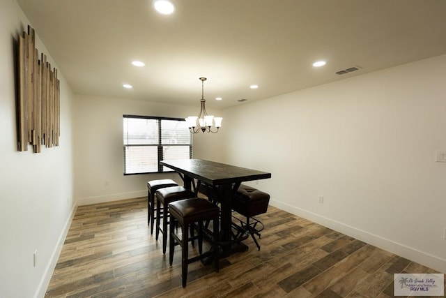 dining area with dark hardwood / wood-style flooring and an inviting chandelier