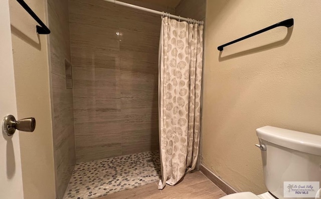 bathroom with toilet, wood-type flooring, and a shower with shower curtain