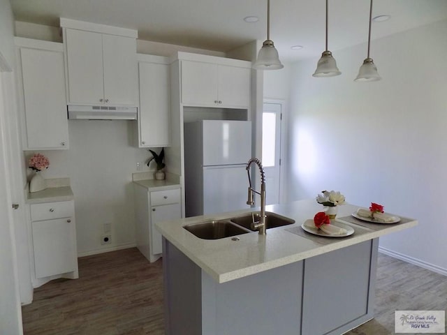 kitchen with decorative light fixtures, white refrigerator, white cabinetry, and sink