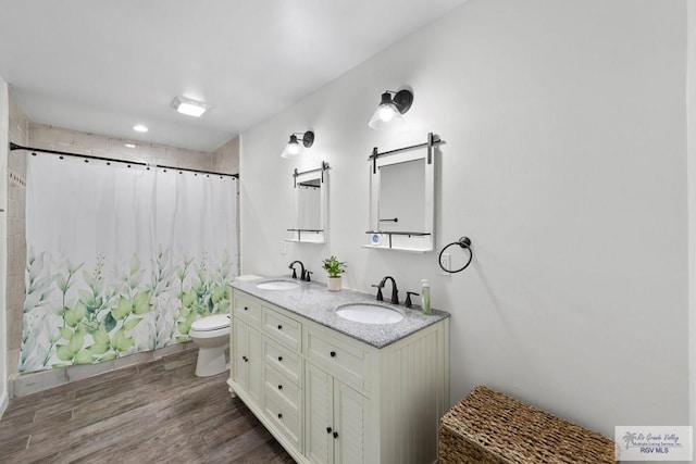 bathroom with hardwood / wood-style flooring, vanity, a shower with curtain, and toilet