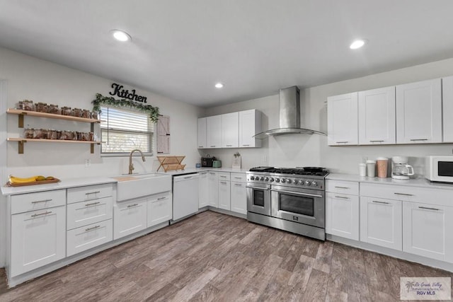 kitchen featuring white cabinets, white appliances, sink, and wall chimney range hood