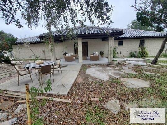 back of house featuring a tiled roof, outdoor lounge area, and a patio area