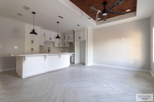 kitchen with a spacious island, light parquet floors, a breakfast bar, and white cabinets