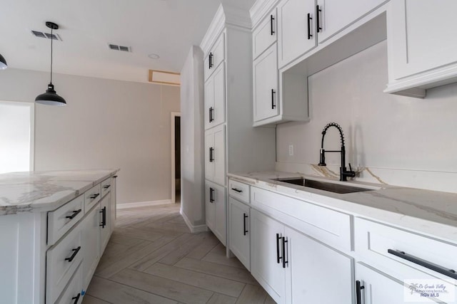 kitchen featuring pendant lighting, light parquet flooring, sink, and white cabinets