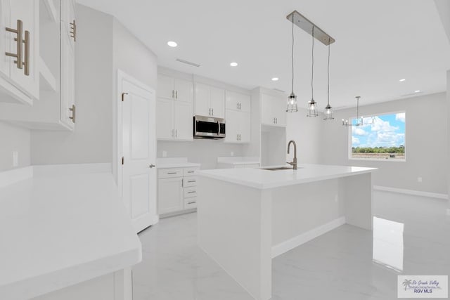 7336 San Andres St, Brownsville, TX 78526 - kitchen featuring stainless steel microwave, a sink, a center island with sink, white cabinetry, and recessed lighting