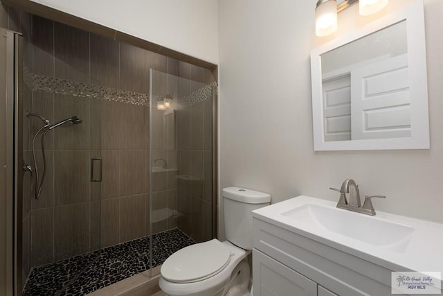 bathroom featuring vanity, toilet, and a shower with door