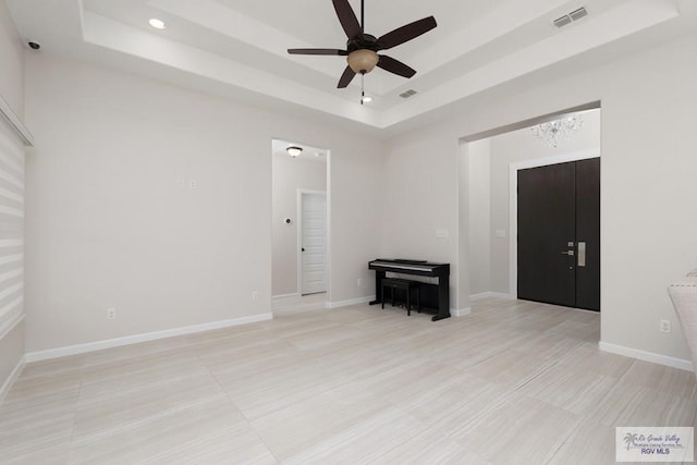 unfurnished room featuring light tile patterned floors, ceiling fan, and a tray ceiling