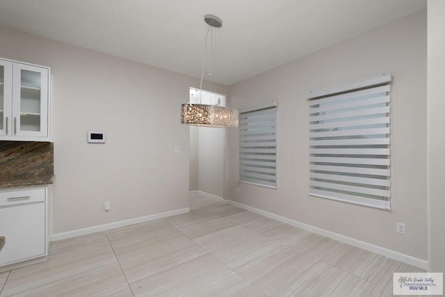 unfurnished dining area featuring light tile patterned floors and a chandelier