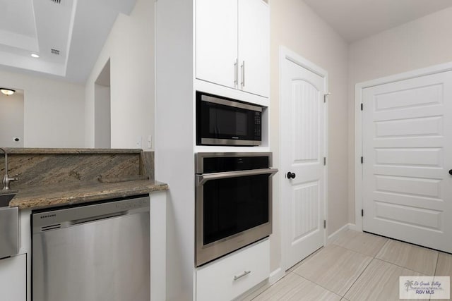 kitchen featuring stone counters, light tile patterned floors, white cabinets, and appliances with stainless steel finishes