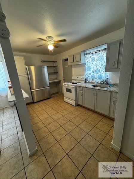 kitchen with stainless steel refrigerator, ceiling fan, sink, white range with electric cooktop, and light tile patterned flooring