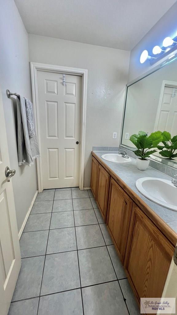 2839 Regency Dr, Brownsville, TX 78526 - bathroom featuring tile patterned floors, double vanity, and baseboards