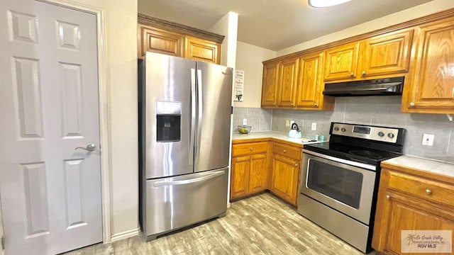 2839 Regency Dr, Brownsville, TX 78526 - kitchen with stainless steel appliances, under cabinet range hood, light wood-style floors, and brown cabinetry