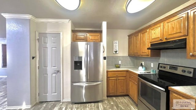2839 Regency Dr, Brownsville, TX 78526 - kitchen with appliances with stainless steel finishes, under cabinet range hood, light wood-type flooring, decorative backsplash, and brown cabinetry