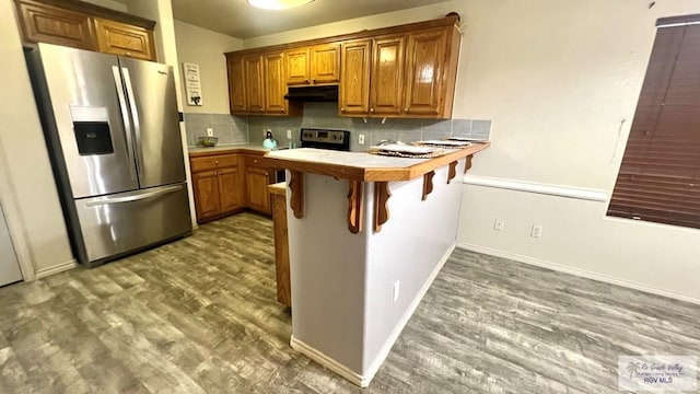 2839 Regency Dr, Brownsville, TX 78526 - kitchen with stainless steel appliances, a peninsula, wood finished floors, tile countertops, and brown cabinetry