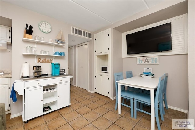 110 E Pompano St, South Padre Island, TX 78587 - kitchen with open shelves, white microwave, white cabinetry, and light countertops